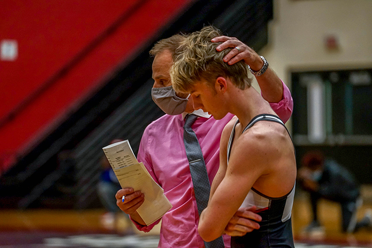 Head wrestling coach Adam Schneider comforts Tide Avant, 11, after a loss during a match against Cane Bay.